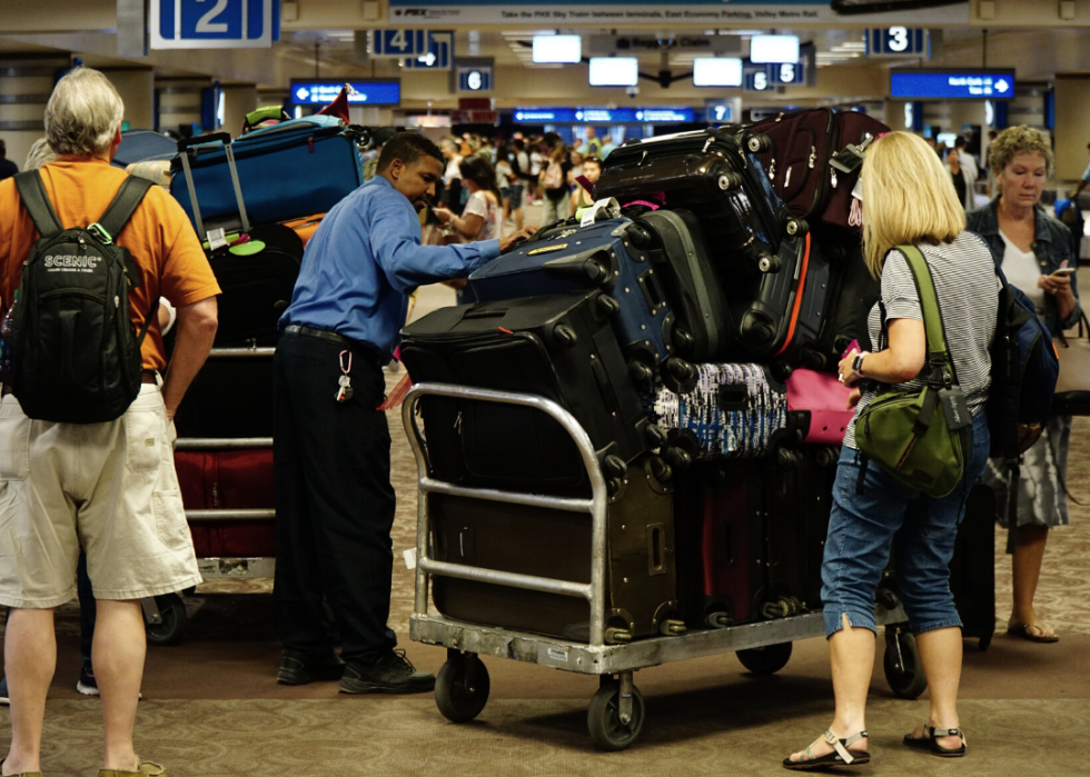 A baggage handler helps passengers retrieve their luggage at Sky Harbor Airport